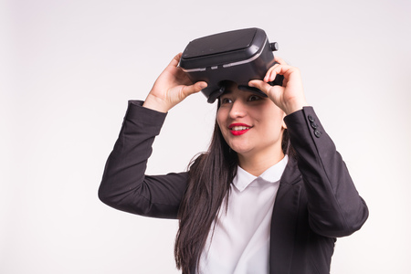 Technologies and people concept - surprised young girl looking with Virtual Reality Glasses and smiles over white backgroundの写真素材