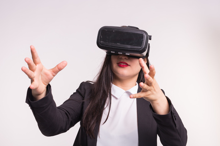Technology and people concept - Amazed young woman touching the air during the VR experience