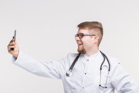 Happy male doctor making selfie on white backgroundの写真素材