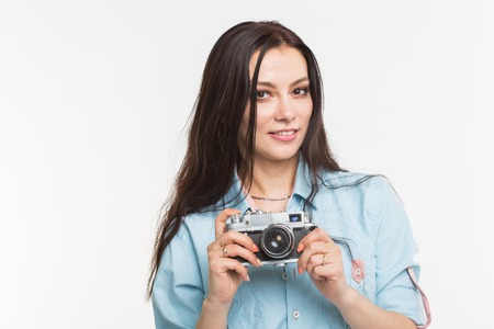 Photographer, hobby and people concept - Young brunette woman with retro camera on white background