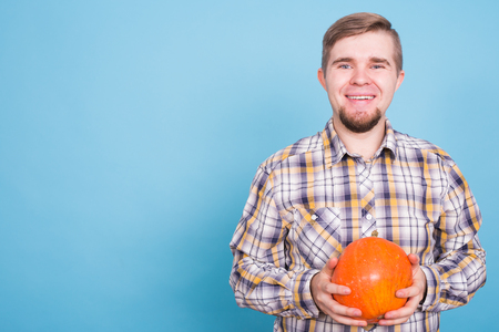 Smiling man holding pumpkins over blue background with copy space - harvest and autumn conceptの写真素材