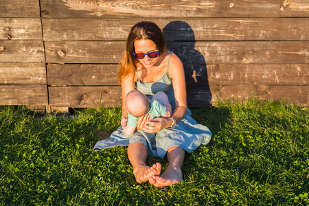 Happy family mother and baby hugging on nature in summerの写真素材