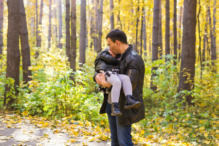 Fatherhood, children and family concept - Father holding his daughter in autumn parkの写真素材