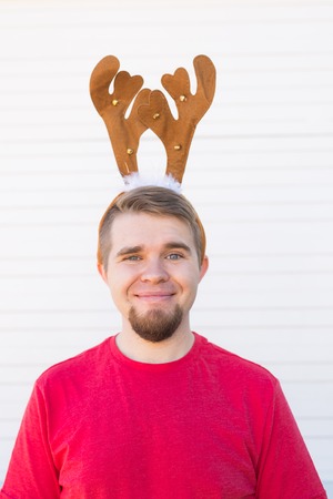 Holidays and christmas concept - Young happy man in deers horns on white backgroundの写真素材