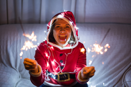 Christmas, holidays and people concept - young happy woman laughing in christmas suit with lights over the white backgroundの写真素材