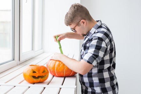 Halloween pumpkin cutting process. Handsome man making Jack-o-lantern.の写真素材