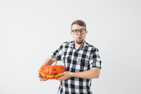 Happy funny man holding a jack o lantern carved halloween pumpkin in light roomの写真素材