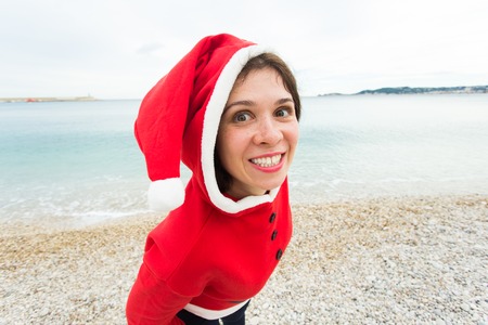 Christmas and holiday concept - Close up portrait of woman in Santa suit over sea background
