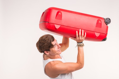 Expression and gesture concept - Young man in white shirt holding red suitcase