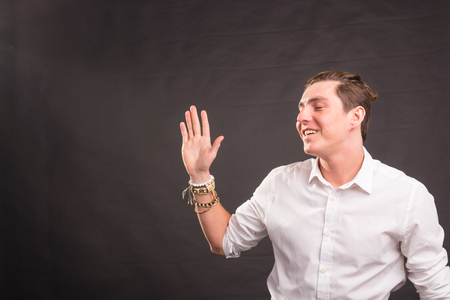 People, gesture and fashion concept - young handsome man waving his hand against brown background with copy spaceの写真素材