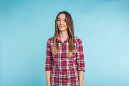 Young european woman standing with serious face in blue backgroundの写真素材