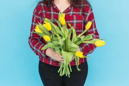 Bunch of yellow tulips on womans hands on blue backgroundの写真素材