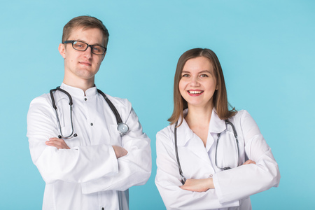 Male and female doctors in white gowns on blue backgroundの写真素材