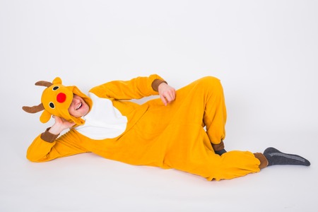 Holiday, Christmas and people concept - Man in reindeer costume lying on the white floor