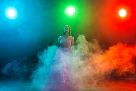 Cheerleading young woman dancing on colourful dark backgroundの写真素材