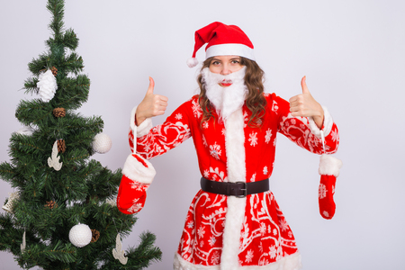 Christmas, fun and emotions concept - funny woman in santa suit and in artificial beardの写真素材