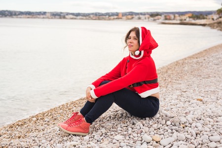 Christmas and holidays concept - dreaming woman in santa costume on sandy beachの写真素材