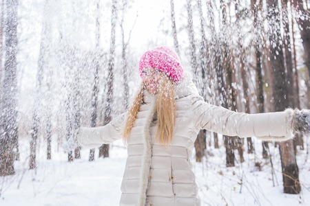 Young pretty woman throwing snow in the air in winter holidaysの写真素材