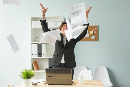 Business people, joke and fun concept - happy funny businessman throwing papers in officeの写真素材