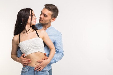Young man hugging his girlfriend on white background with copy spaceの写真素材