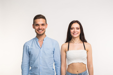 Emotions, fun and people concept - young couple stand near each other and smiling over the white backgroundの写真素材