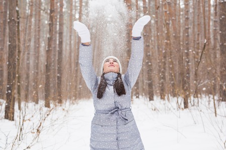 Happy young woman plays with a snow at snowy forest outdoorの写真素材