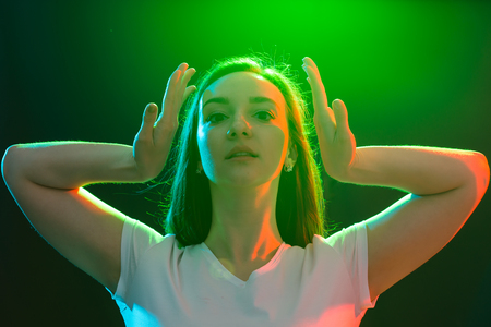 Dance, jazz funk, sport and people concept - young woman dancing in darkness and holds her hands...