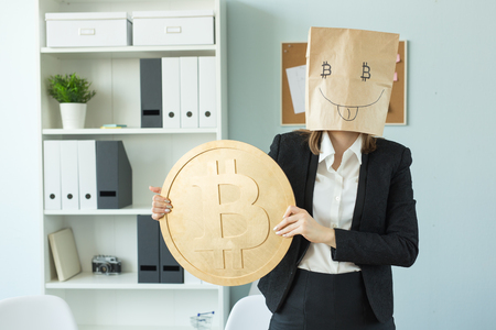 Crypto currency, money, blockchain concept - funny woman with package on her head show us a huge bitcoin. She looks like crazyの写真素材