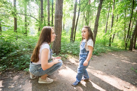Nature, motherhood and child concept - Happy mother and little daughter have fun in green parkの写真素材