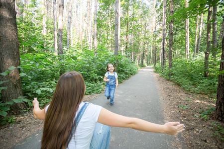 Nature, family, people concept - Adorable little kid girl and young woman in beautiful forest. Daughter running to motherの写真素材