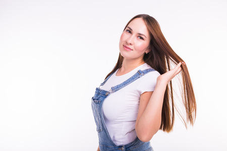 Portrait of a smiling pretty woman in denim overall isolated on white background with copy spaceの写真素材