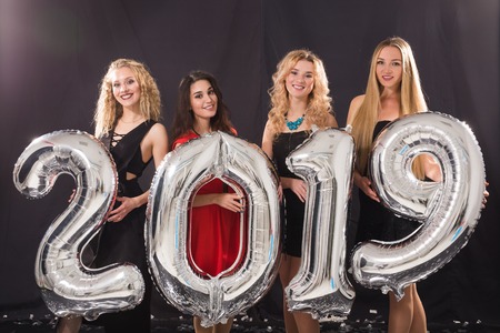 New 2019 Year is coming. Group of cheerful young women holding silver colored numbers on the party.の写真素材