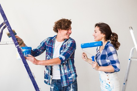 Repair, renovation and love couple concept - Young woman and man doing repair with happy faces