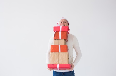 Christmas and holidays concept - man in santa hat with many gifts on white background with copy...