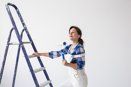 Redecoration, renovation, new home and people concept - young attractive brunette woman doing repair by herselfの写真素材