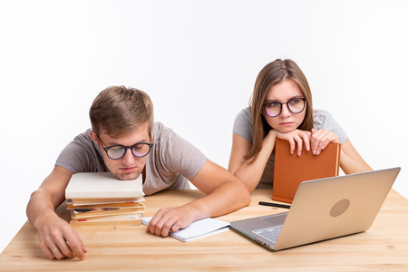Education and people concept- a couple of young people in glasses look like they are bored of learning homeworkの写真素材