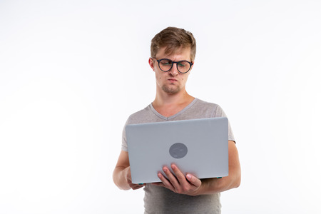 Study, education and people concept - a young handsome man look at netbook and thinking doing exercises on white backgroundの写真素材