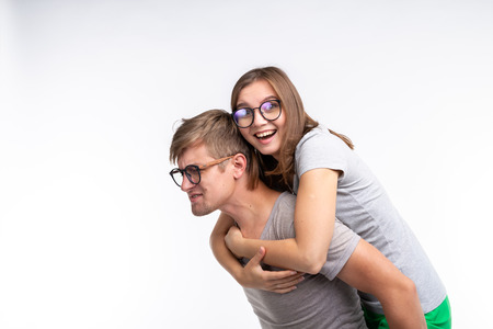 Education, funny people and joke concept - a young woman jumped on a back of man. They are happyの写真素材