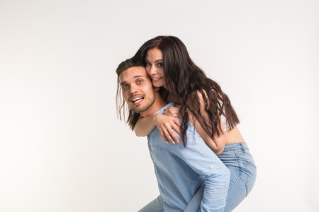 Emotional, love and people concept - young woman climbed the guy on the back and they happy and...