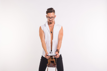 People, photo and style concept - happy young man taking selfie with old photo camera on white backgroundの写真素材