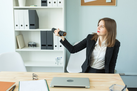 Business, emotions and people concept - Woman in office holding dumbbells in handsの写真素材