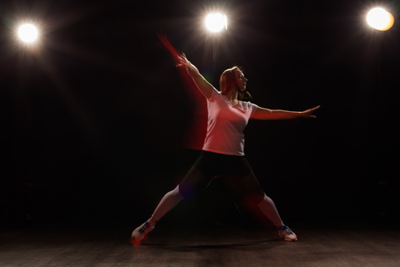 Dancing, sport, beautiful and people concept - young woman dancing in darkness jumped in colourful lightの写真素材