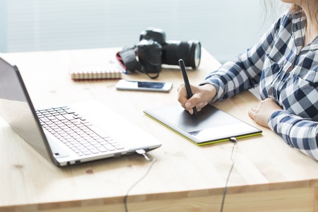 Business, technology and people concept - woman use designer tablet in working at laptopの写真素材