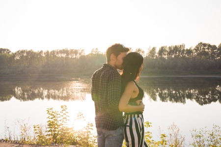 People, love and nature concept - Young beautiful woman and handsome man embracing each other over...
