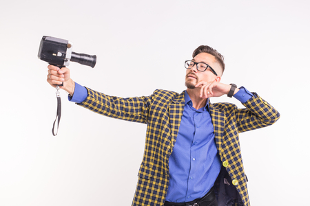 Technologies, photographing and people concept - portrait of funny young brunette man taking selfie with camera on white backgroundの写真素材