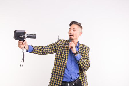 Technologies, photographing and people concept - portrait of funny young brunette man taking selfie with camera on white backgroundの写真素材