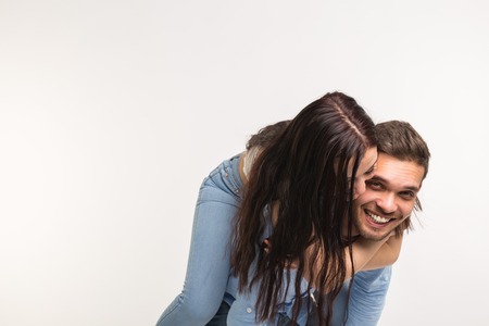 Fun and relationship concept - Man carrying girlfriend on his back on white backgroundの写真素材