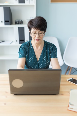 Business people and technology concept - Middle aged business woman working on laptop in her officeの写真素材