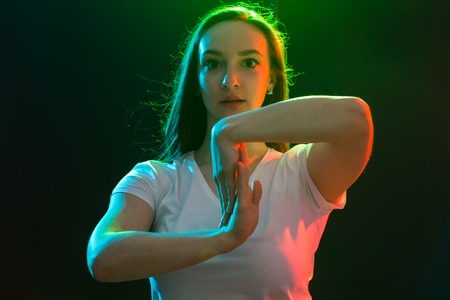 People, jazz funk and dance concept - young woman dancing in darkness and holds one hand near her faceの写真素材