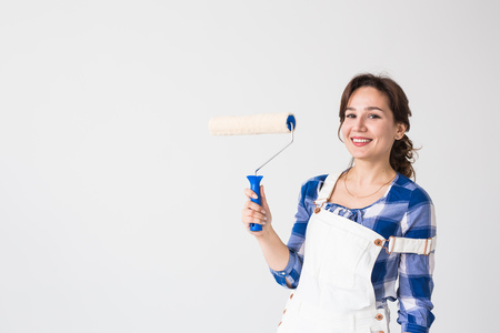 Repair, renovation, new home and people concept - Beautiful woman paints the wall during redecoration with copy spaceの写真素材